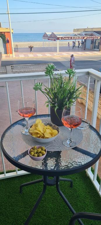a table with two wine glasses and a plate of food at Emma Apartman in Santa Pola