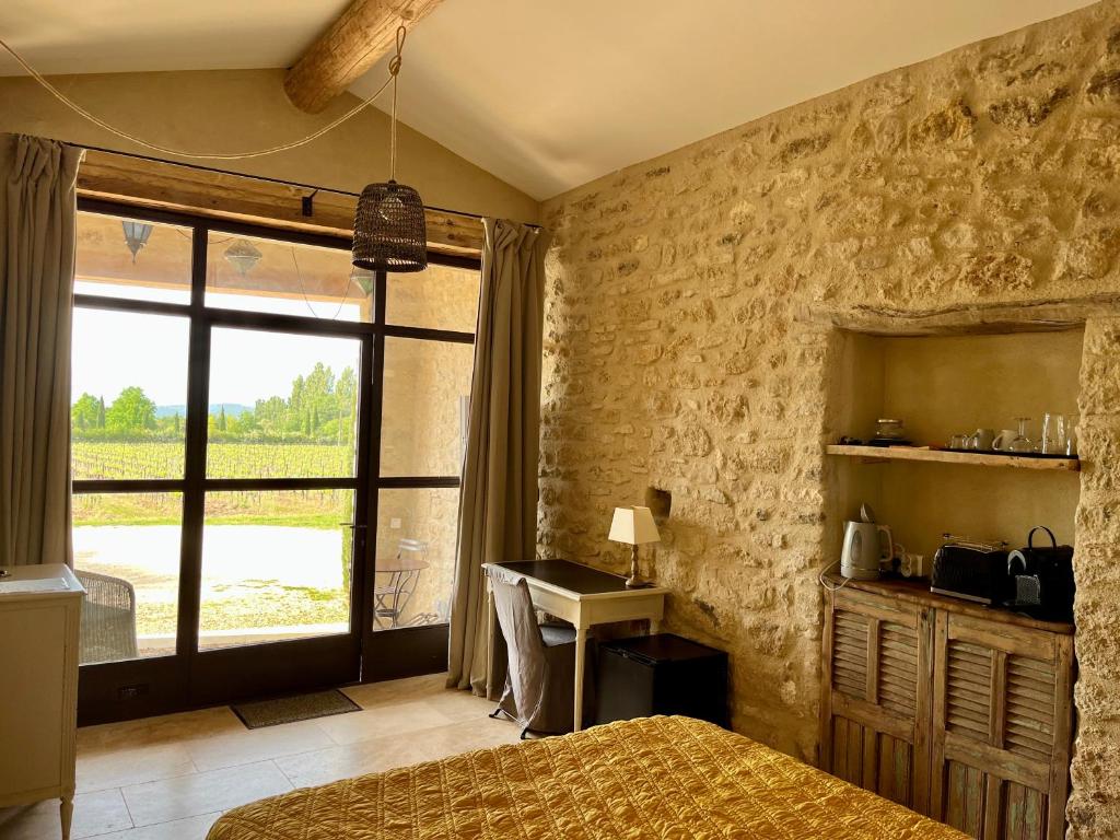 a bedroom with a bed and a desk and a window at La Verrière à Bonnieux in Bonnieux