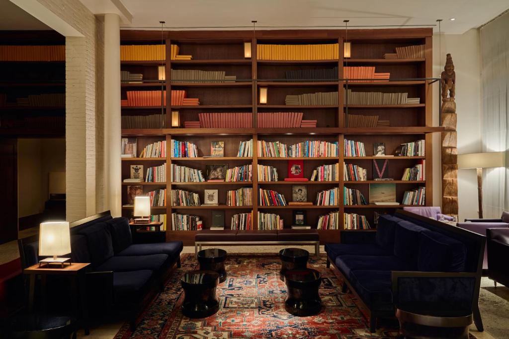 eine Bibliothek mit zwei blauen Sofas und Bücherregalen in der Unterkunft The Mercer in New York