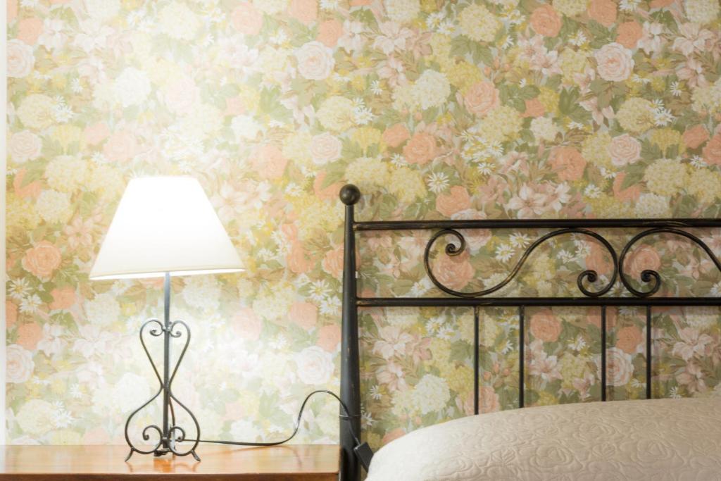 a bedroom with a bed with a lamp and floral wallpaper at Terrazza sul Parco in Modica