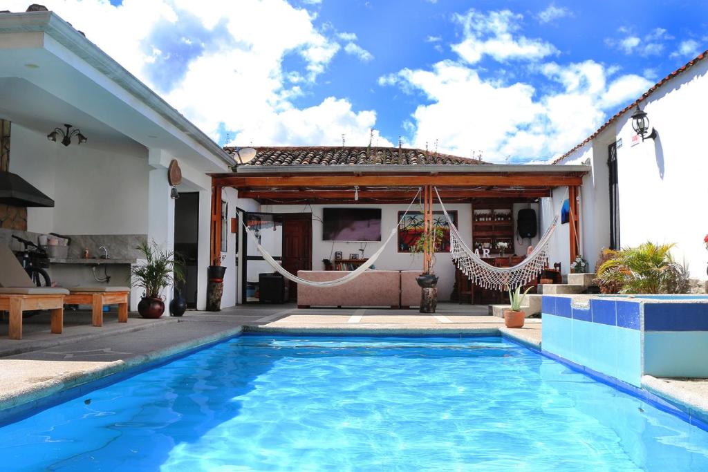 a house with a swimming pool and a patio with hammocks at Hostel las Palmas in Vilcabamba
