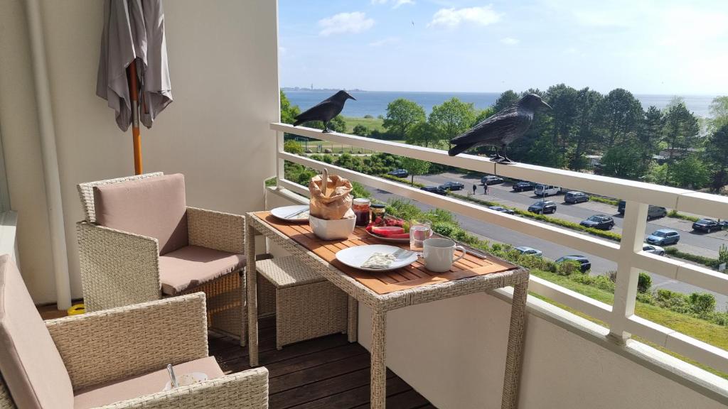 two birds sitting on a balcony with a table and chairs at Meerblick Ferienwohnung in Sierksdorf