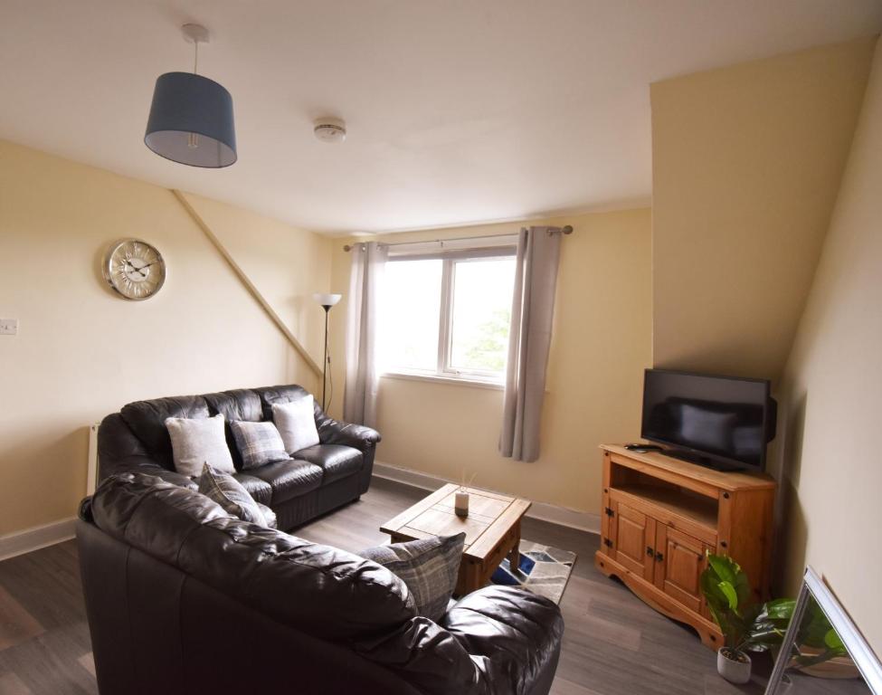 uma sala de estar com um sofá de couro e uma televisão em Jovie Apartment em Stornoway
