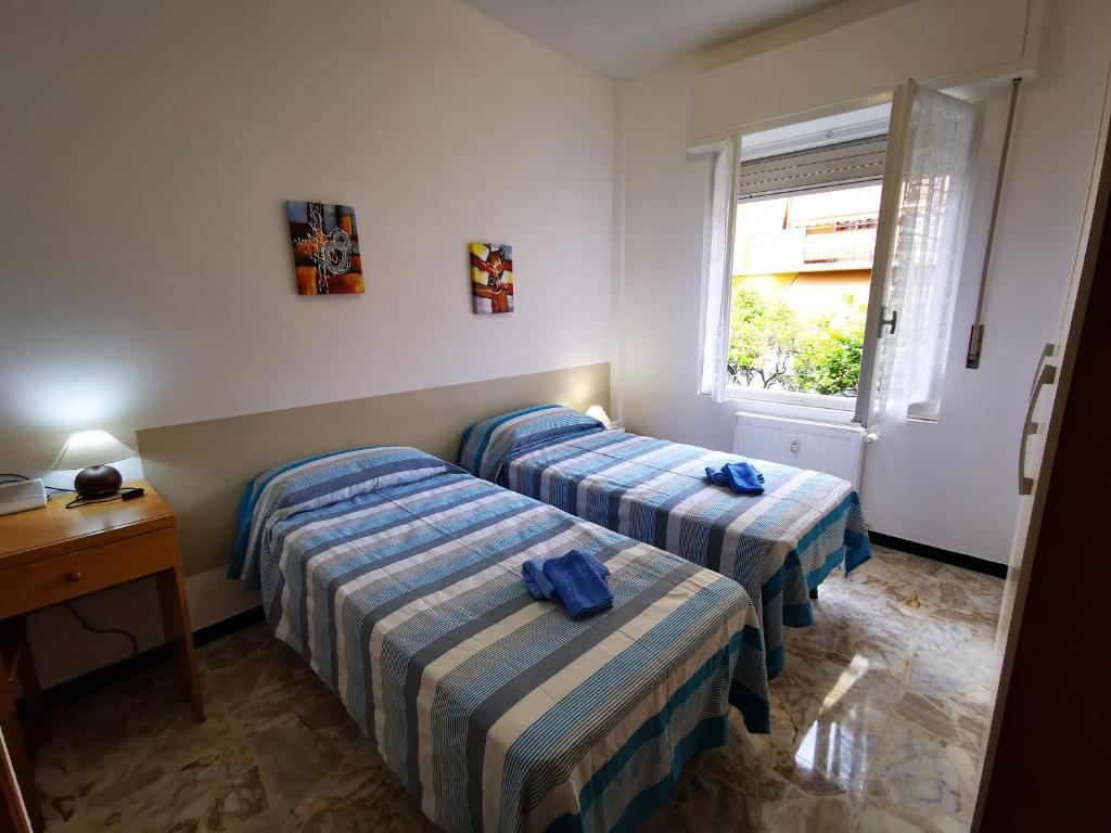 una camera d'albergo con due letti e una finestra di Casa Serena a Bordighera