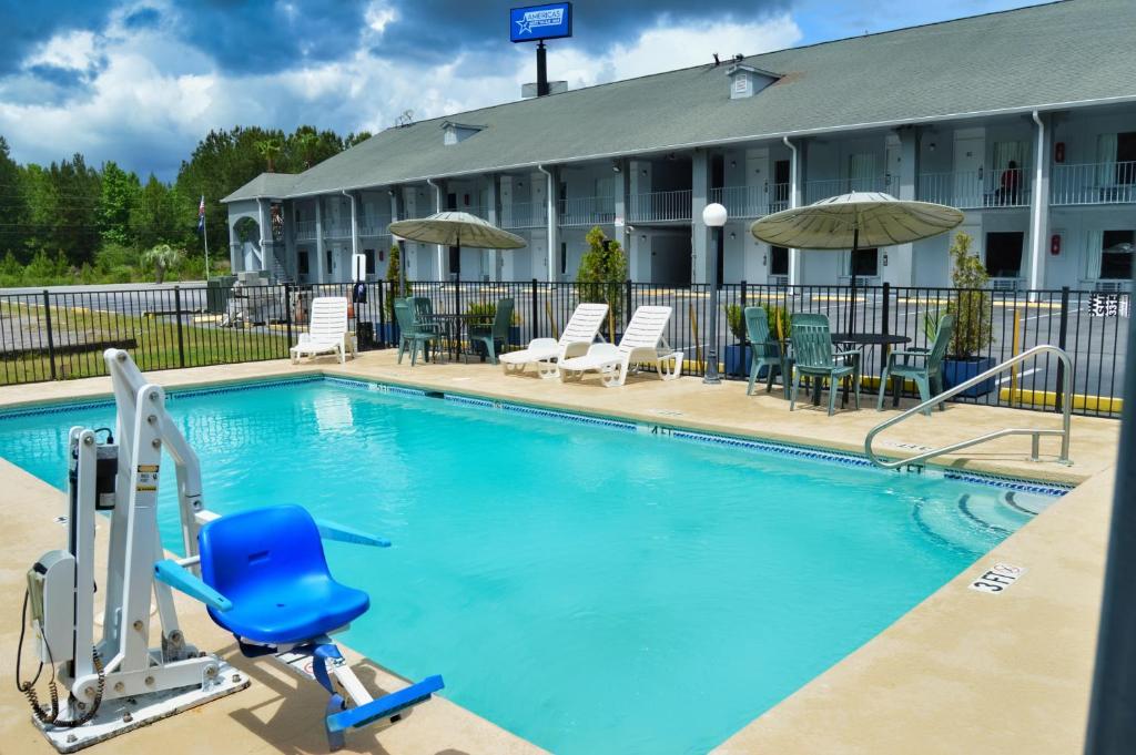 a pool in front of a hotel with a blue chair at Days Inn by Wyndham Hardeeville Near Hilton Head in Hardeeville