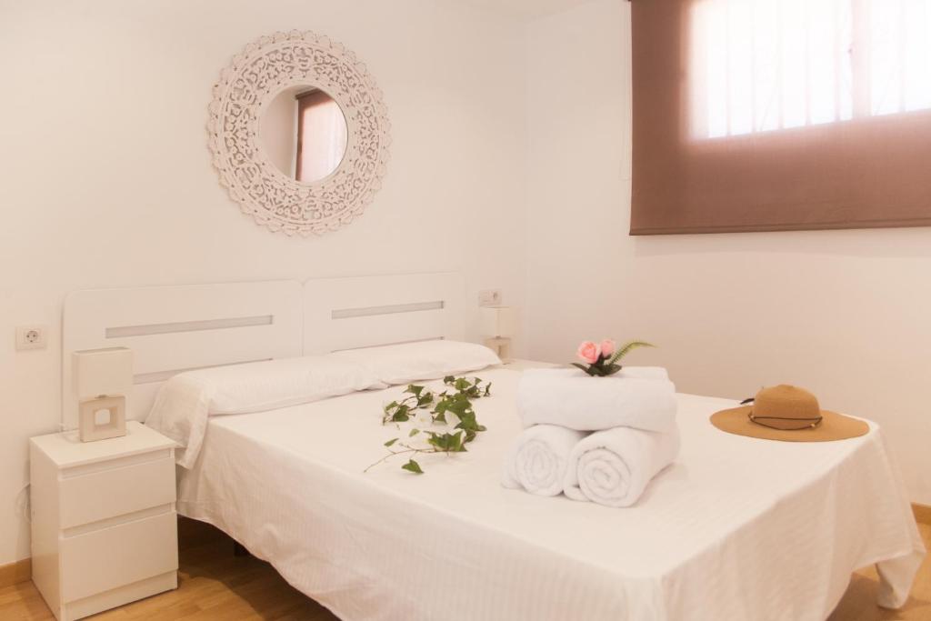 um quarto branco com uma cama com toalhas e um espelho em Apartamentos Thaisay LUZ DEL MAR I em Puerto del Carmen