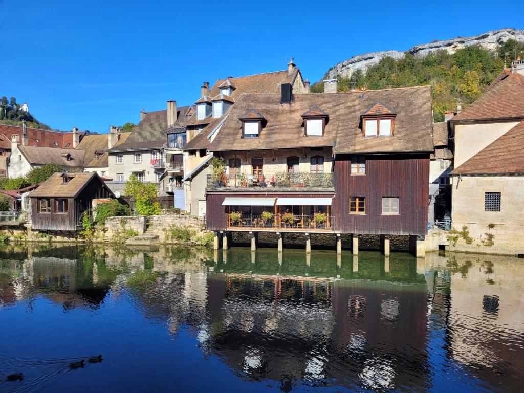 a building sitting on the water next to a river at Gite l ORIGINE in Ornans