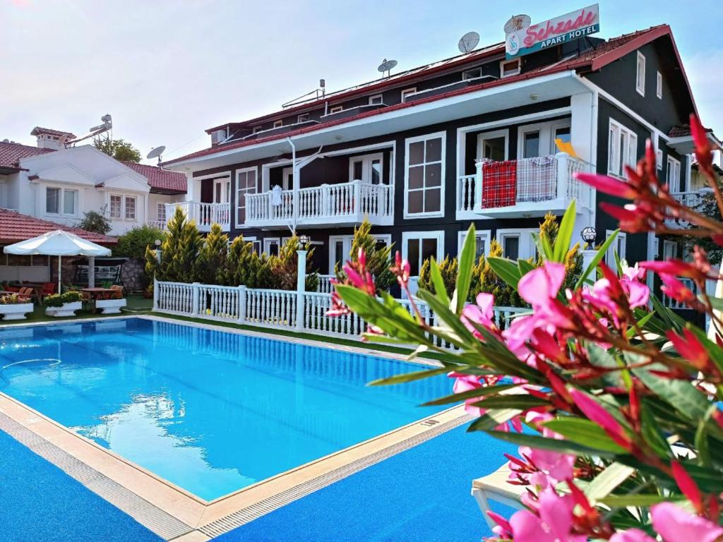 a villa with a swimming pool in front of a house at Şehzade Apart Otel in Fethiye