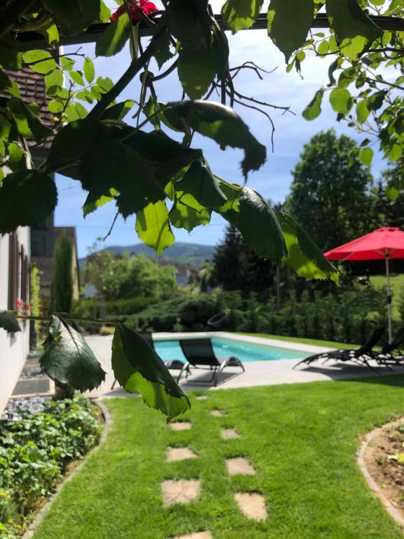 een tuin met een zwembad en groen gras bij Les Chambres Chez Christine in Ottrott