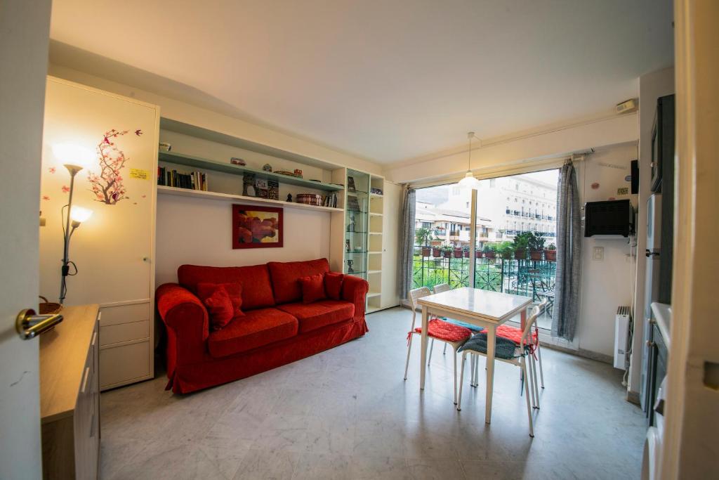 ein Wohnzimmer mit einem roten Sofa und einem Tisch in der Unterkunft Victoria Appartement in Menton