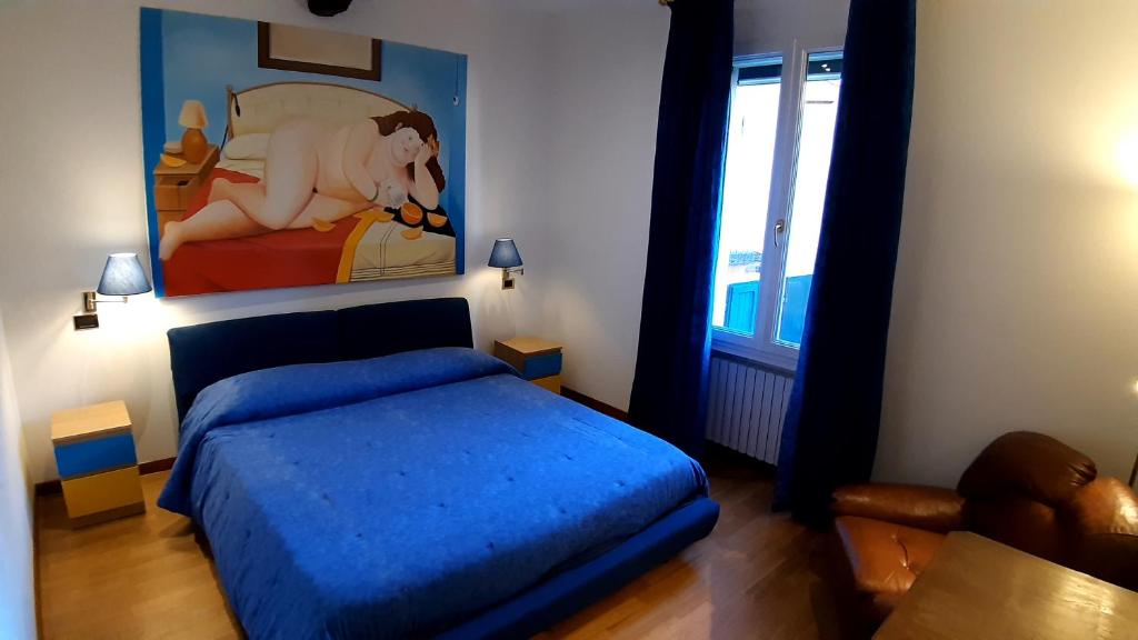 a bedroom with a blue bed and a painting on the wall at La casa di Sacco - Appartamento Bologna Centro in Bologna