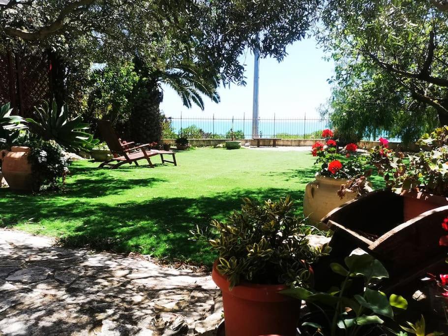 un parc avec des bancs et des fleurs dans l'herbe dans l'établissement Villa Emily, à Licata