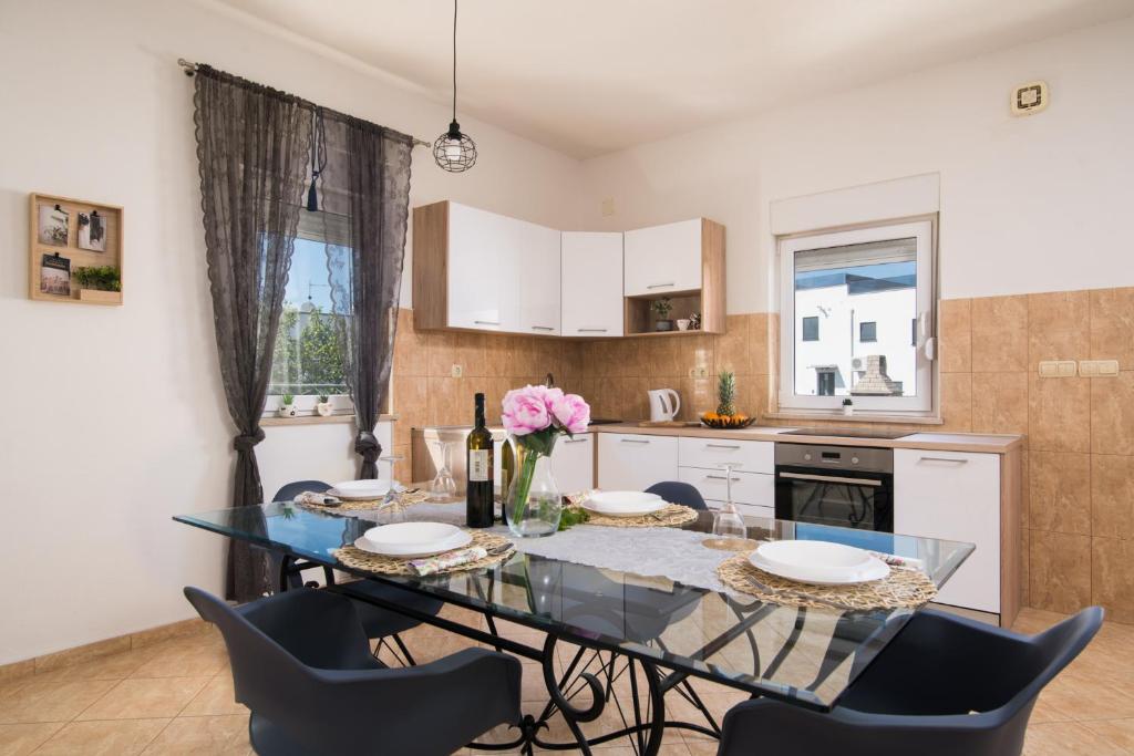 a kitchen and dining room with a glass table and chairs at Apartments Marinera in Trogir