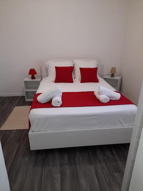 1 dormitorio con 1 cama blanca grande con almohadas rojas en Chez Lucile et Gilbert, en Bouillante
