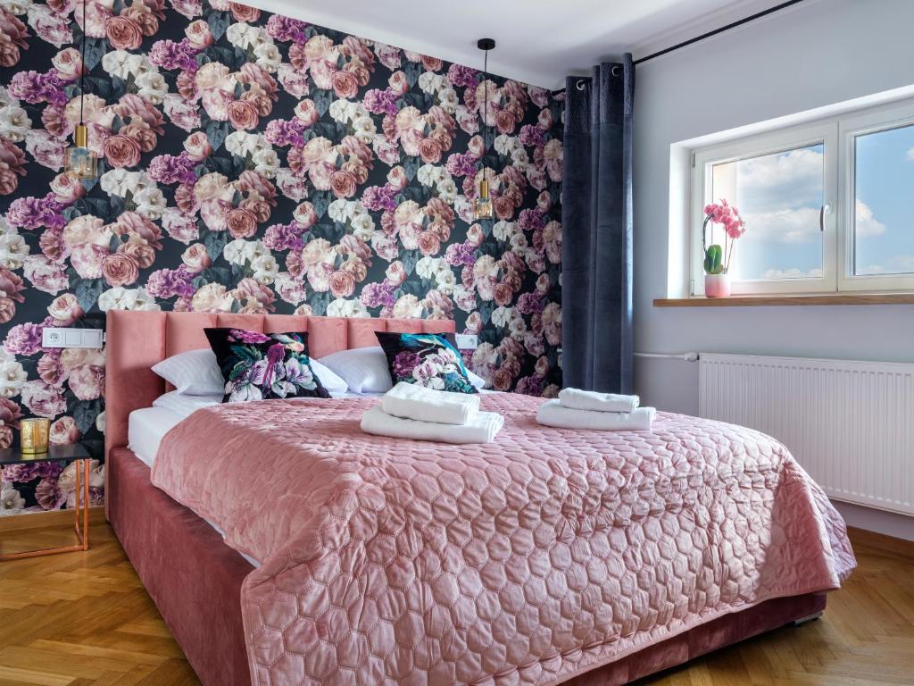 a bedroom with a pink bed with a floral wall at CracWoW City Center Apartment in Krakow