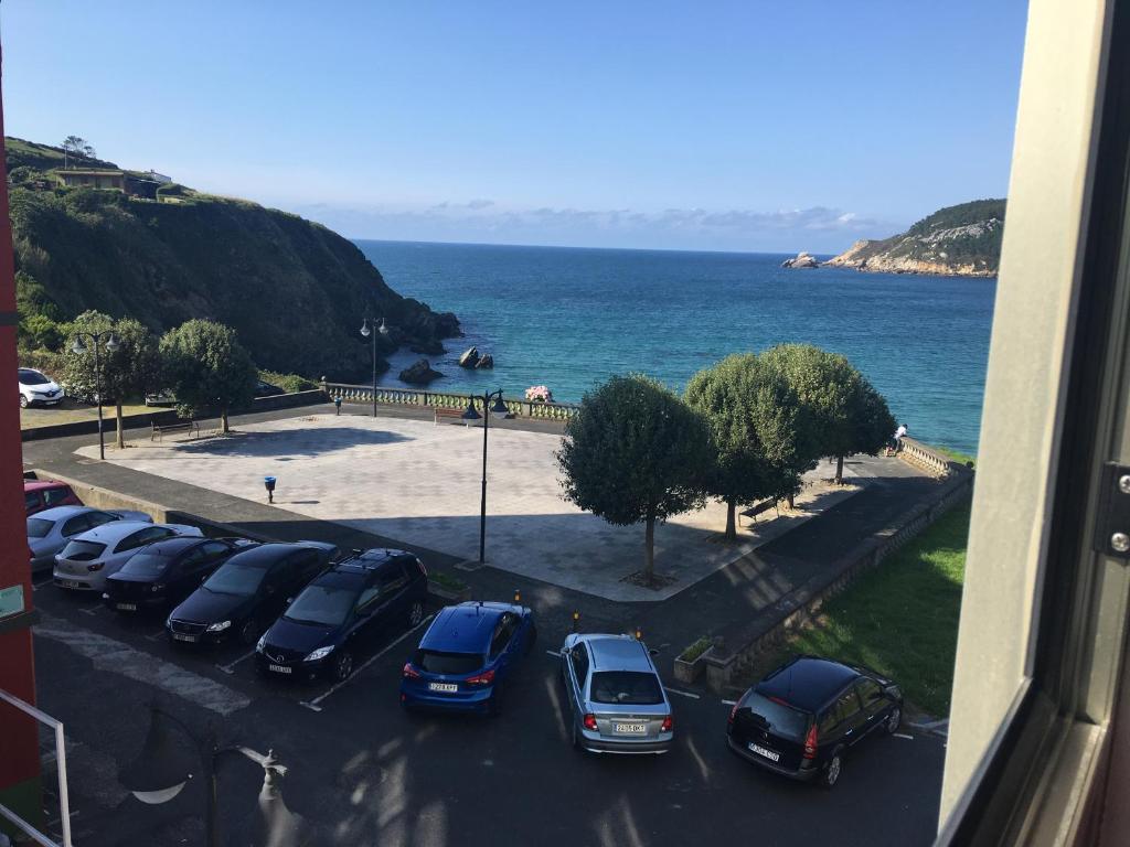 un gruppo di auto parcheggiate in un parcheggio vicino all'oceano di Apartamentos Galicia Norte a O Porto de Espasante