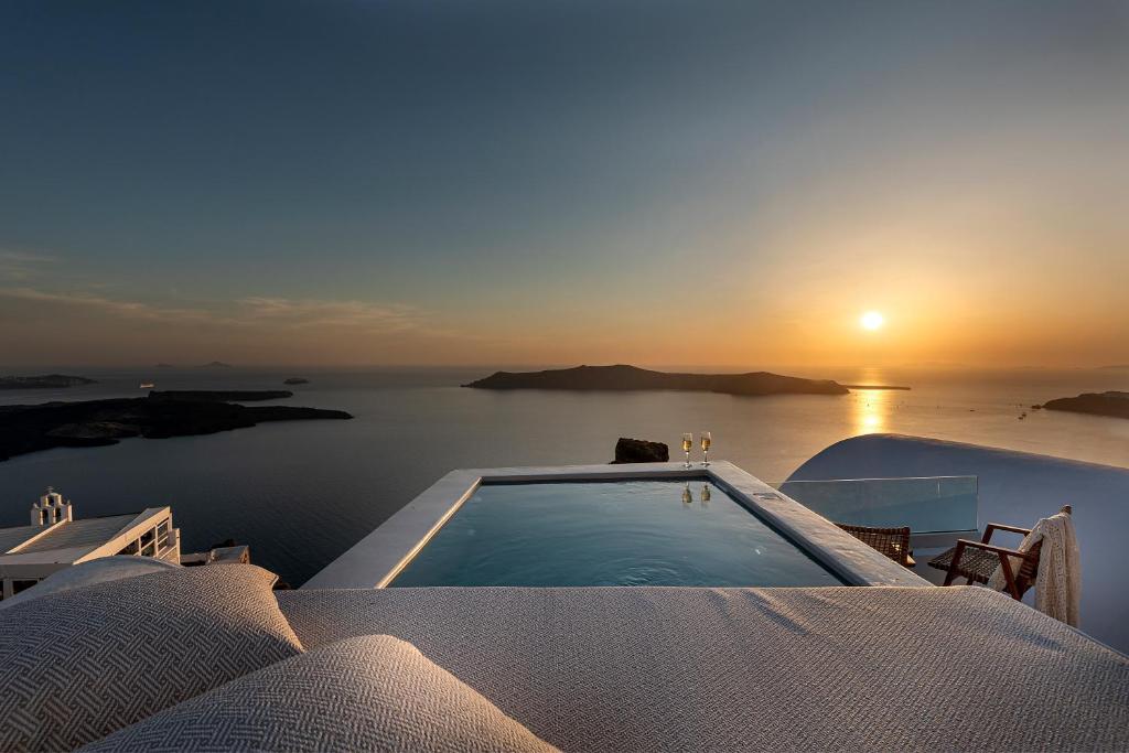 a swimming pool on a house with the sunset at Kaleidoscope Imerovigli Suites in Imerovigli