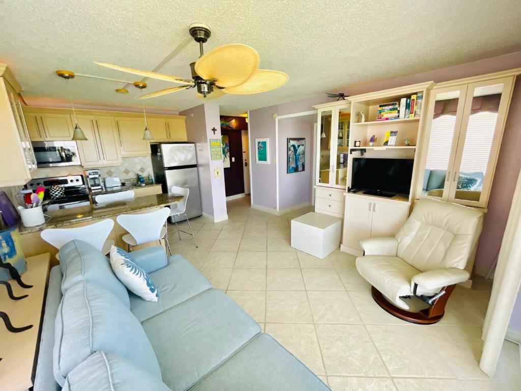 a living room with a blue couch and a kitchen at #903 Panoramic Ocean View at Lovers Key Beach Club in Fort Myers Beach