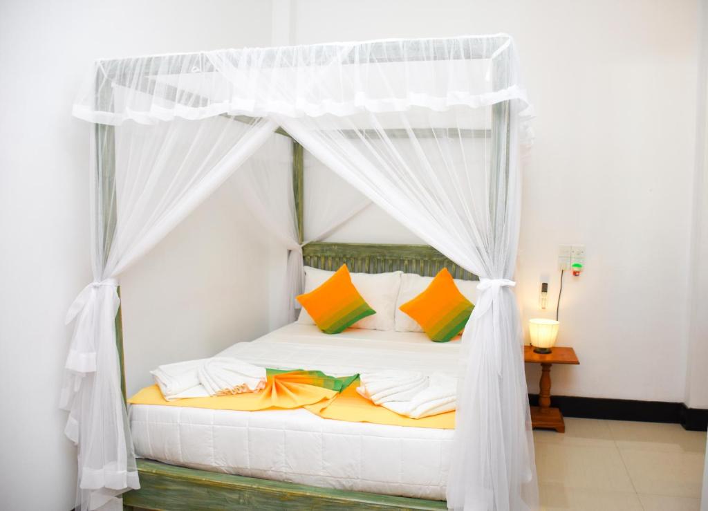 a bedroom with a white canopy bed with colorful pillows at The Entrance Galle Fort in Galle