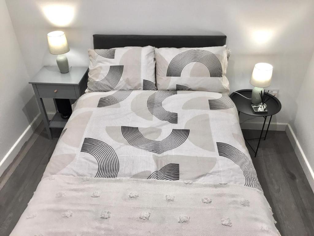 a bed with a black and white comforter and pillows at Dunamis Staycation 3 in Croydon