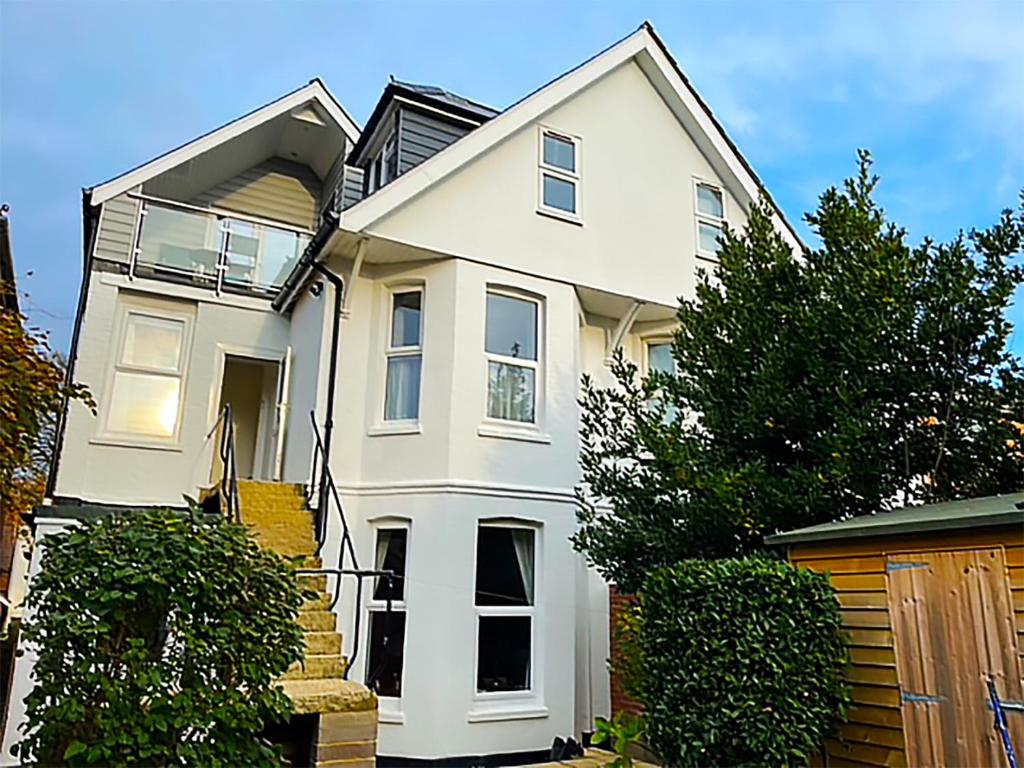 una casa blanca con una valla delante en Private Two Bedroom Residence in Southbourne - Private Parking - Off the High Street - Minutes Away from the Beach, en Bournemouth