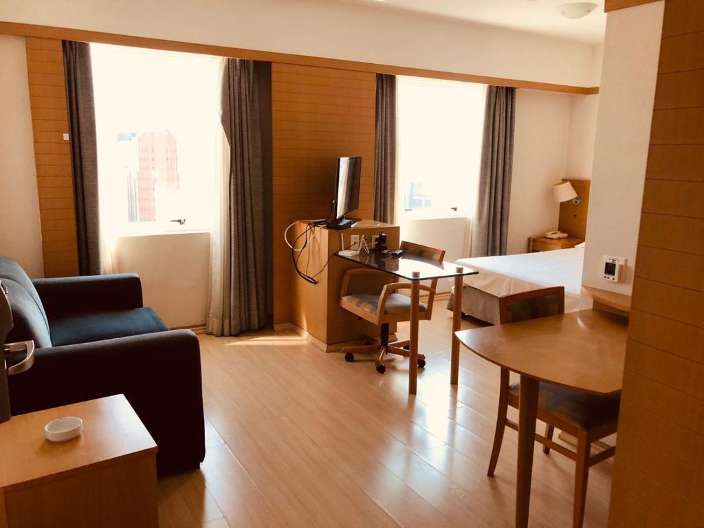 a living room with a couch and a desk with a television at Classic Flat do Eduardo in Sao Paulo