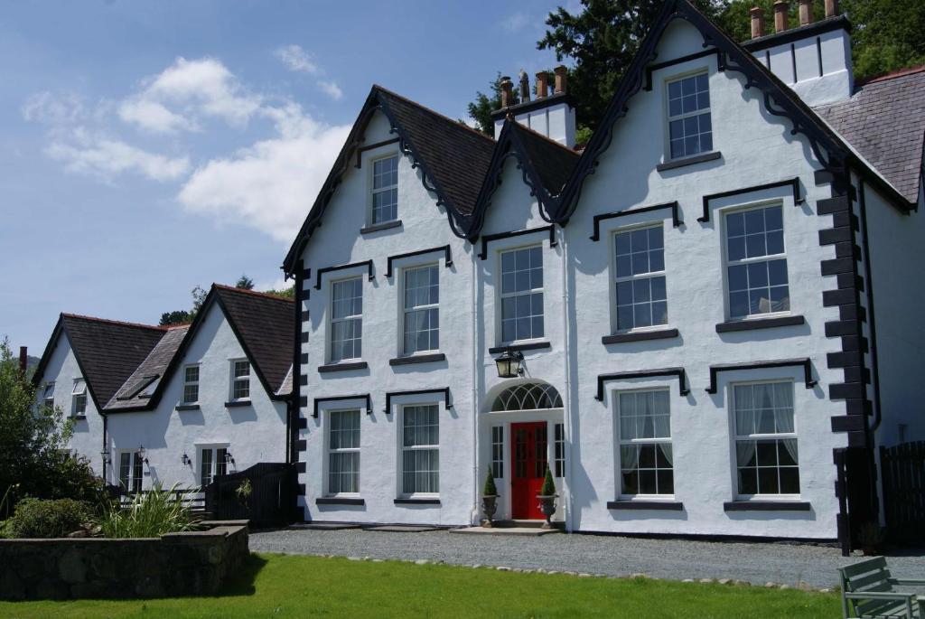 uma fila de casas brancas com uma porta vermelha em Coed Mawr Hall Bed & Breakfast em Conwy