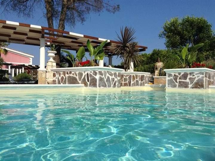 a swimming pool with blue water in a yard at La Maison Rouge b&b in Ginosa Marina