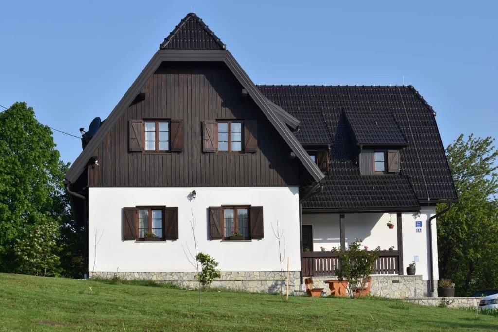 une maison blanche avec un toit noir dans l'établissement FLORA HOUSE, à Rastovača