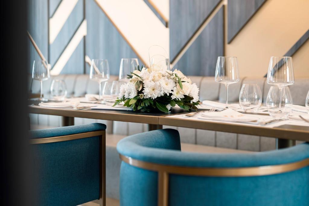 a table with plates and glasses and a bouquet of flowers at Hotel Millennium by Aycon in Budva