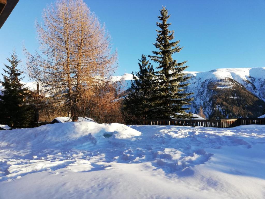 uma pilha de neve com árvores e montanhas ao fundo em Residence Edelweiss em Bellwald