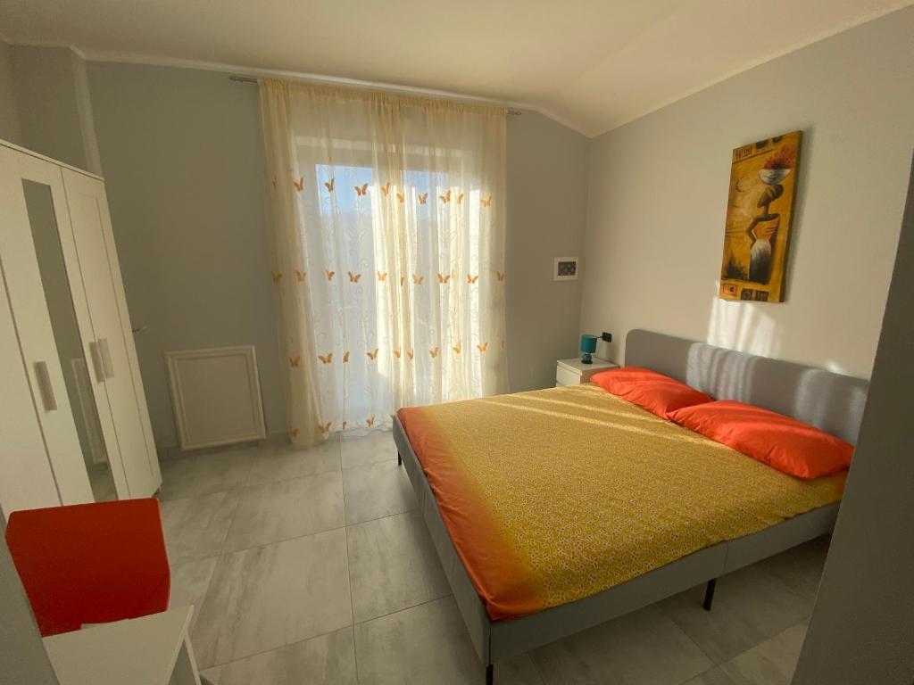 ein Schlafzimmer mit einem Bett mit orangefarbener Bettwäsche und einem Fenster in der Unterkunft B&B Santa Colomba in Benevento