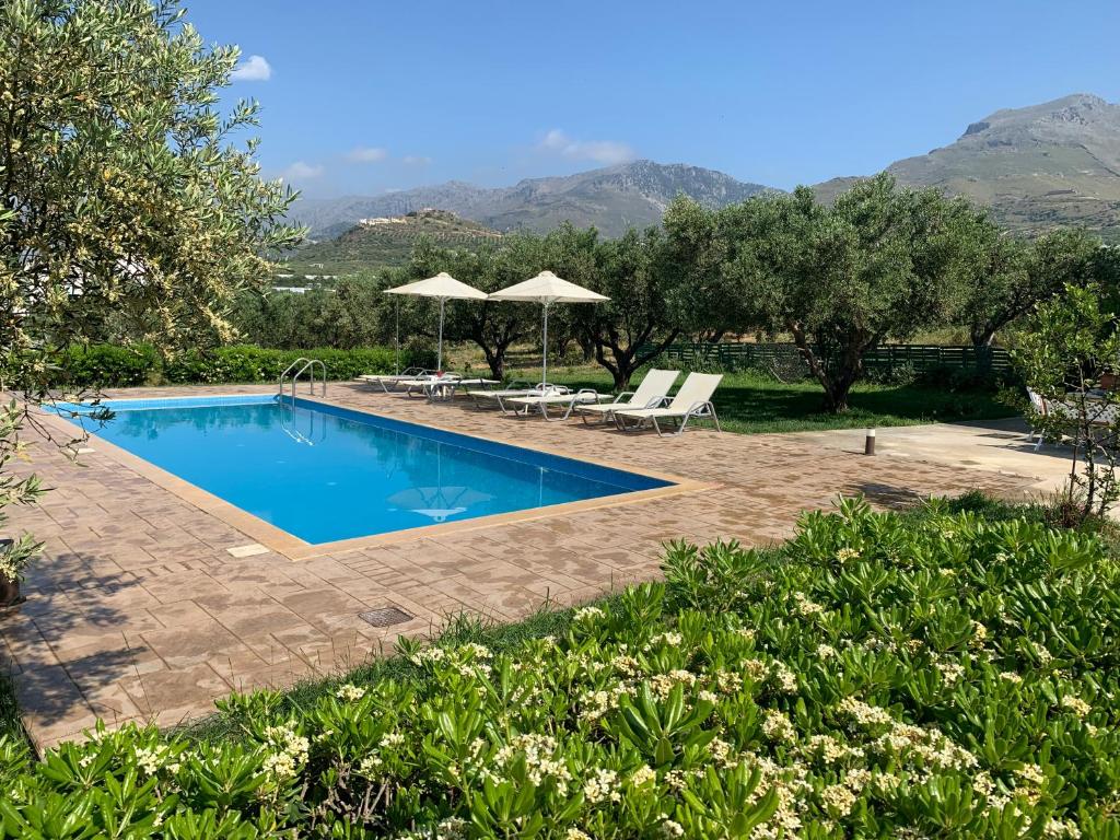 a swimming pool with two chairs and an umbrella at Kassiani Studios in Plakias