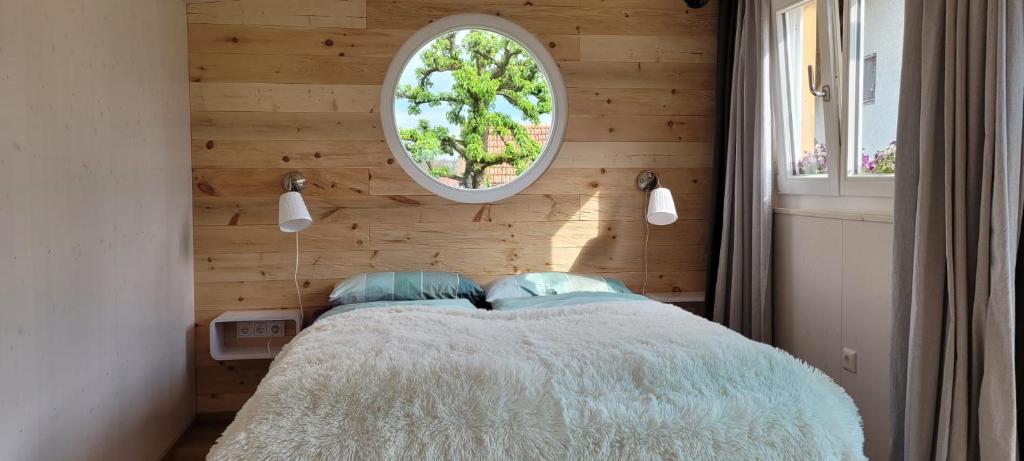 a bedroom with a bed and a round window at Haus mit stilvoller Ferienwohnung und Tiny House nahe Ammersee für 2-6 Personen in Geltendorf