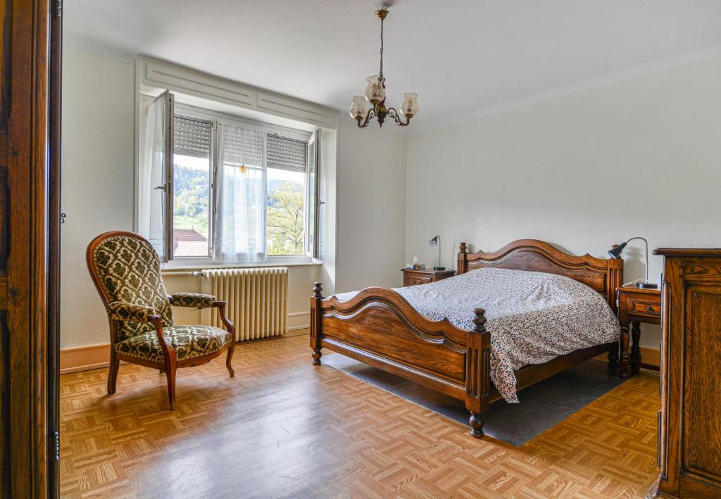 een slaapkamer met een bed, een stoel en een bureau bij Gîte Le Noisetier in Munster