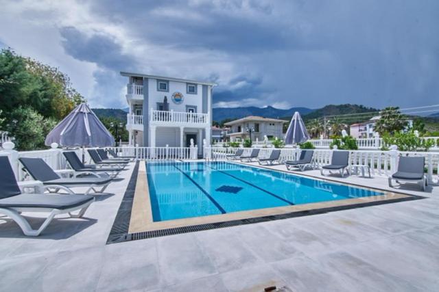 a swimming pool with lounge chairs and a building at Belinda Apartments in Kemer