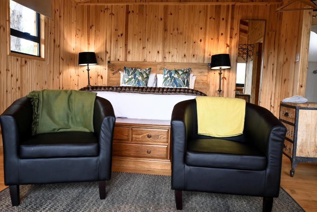 2 Stühle vor einem Bett in einem Schlafzimmer in der Unterkunft Nature's Loft in Fouriesburg