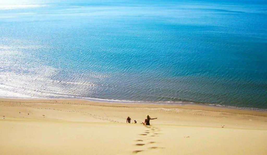a group of people walking on a beach with a surfboard at Hotel MARIO, Shengjin in Shëngjin