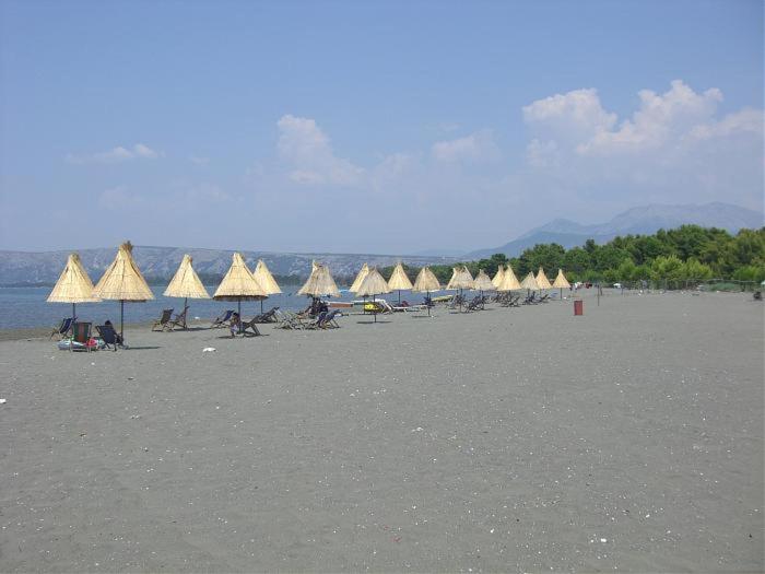 a group of people sitting on a beach with umbrellas at Hotel MARIO, Shengjin in Shëngjin