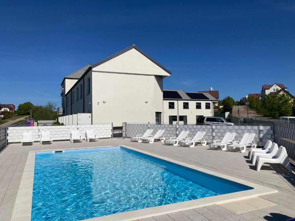 a swimming pool with lounge chairs and a building at Sofia Pokoje z łazienką i aneksem kuchennym in Jarosławiec