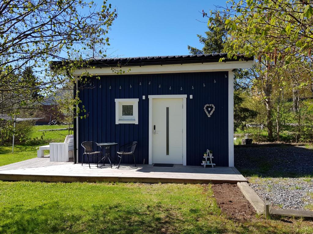 un cobertizo azul con una mesa y sillas. en Lillhuset nära Stockholm en Tungelsta
