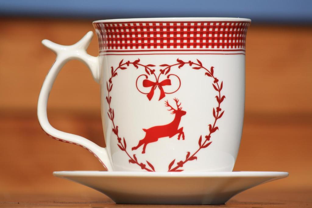 a coffee cup with a reindeer on a saucer at Ferienwohnung Rothirsch in Bad Sachsa