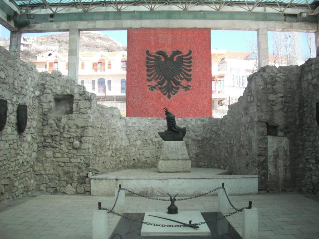 a statue in front of a stone wall with a flag at Hotel MARIO, Shengjin in Shëngjin