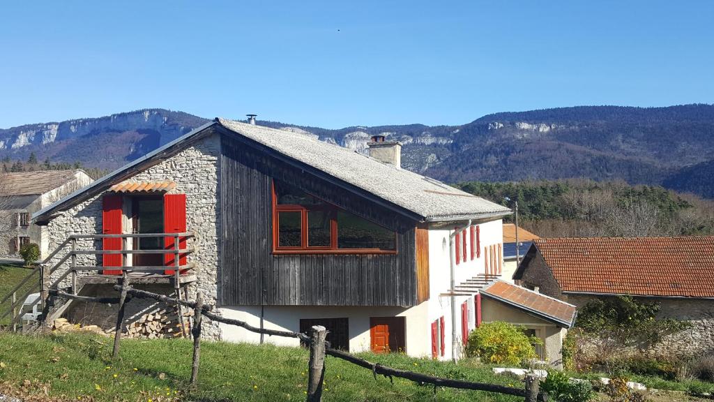 uma pequena casa de pedra com janelas vermelhas numa colina em Gîte BARD des OURS em Saint-Martin-en-Vercors