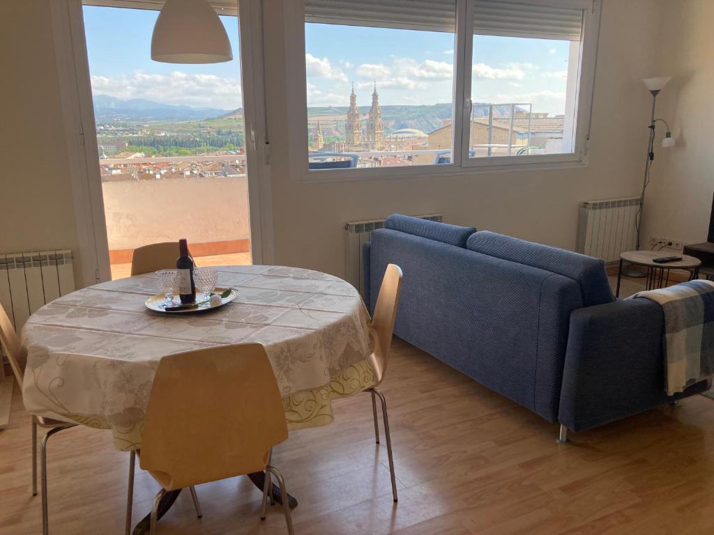 ein Wohnzimmer mit einem Tisch und einem blauen Sofa in der Unterkunft ATICO LOGROÑO CENTRO con garaje incluido 2 in Logroño