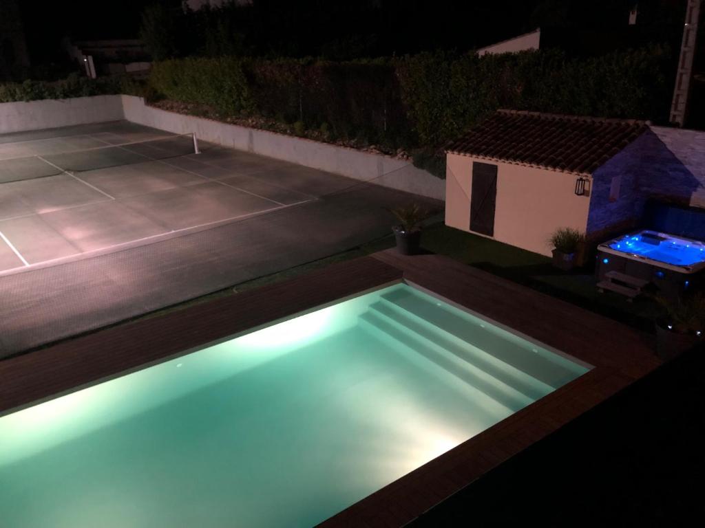 a swimming pool with blue lights in a yard at night at Mas Jasmin in Rochefort-du-Gard