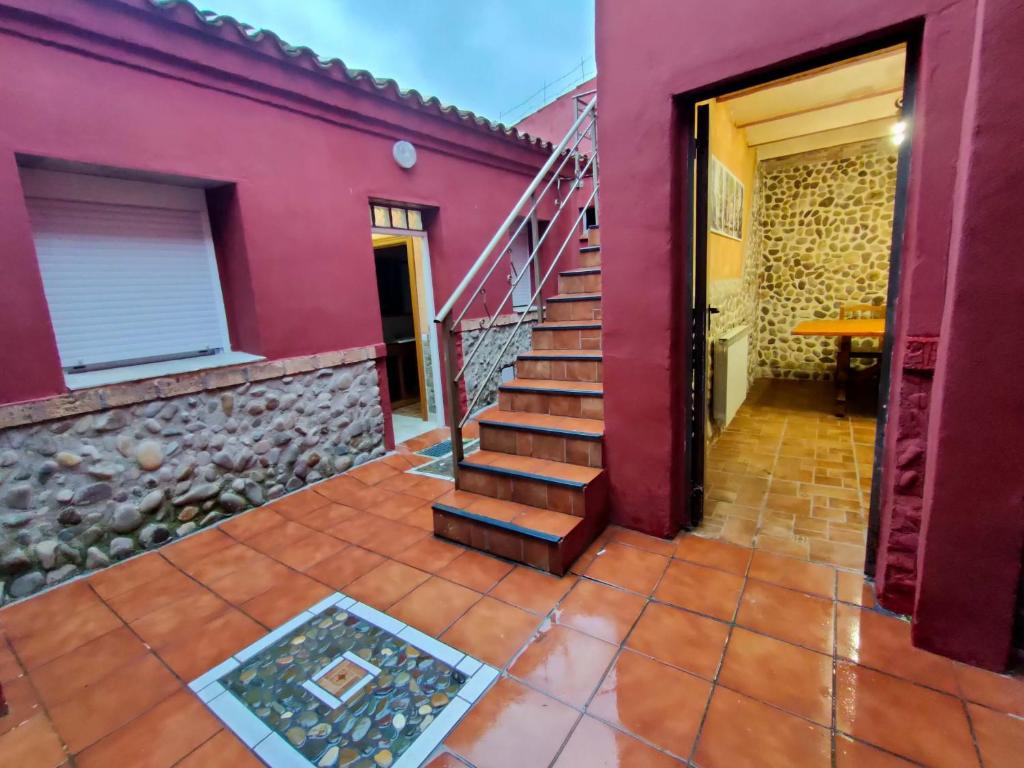 een trap in een rood huis met een stenen muur bij Casa el Susurro in Villamediana de Iregua