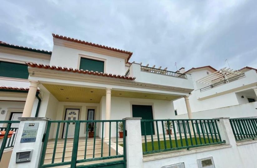 a white house with a green fence in front of it at Zulla Moradia T3, Praia do Norte in Nazaré