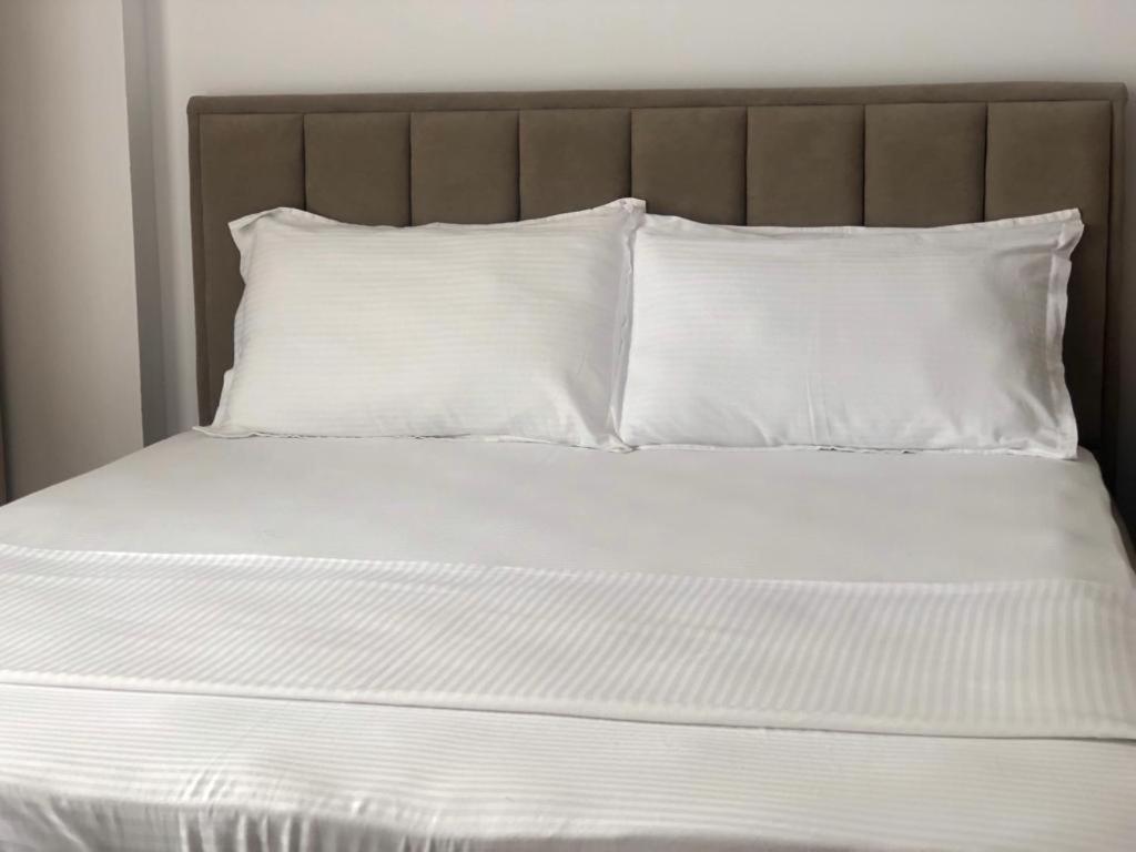 a bed with white sheets and pillows at Hotel MARIO, Shengjin in Shëngjin
