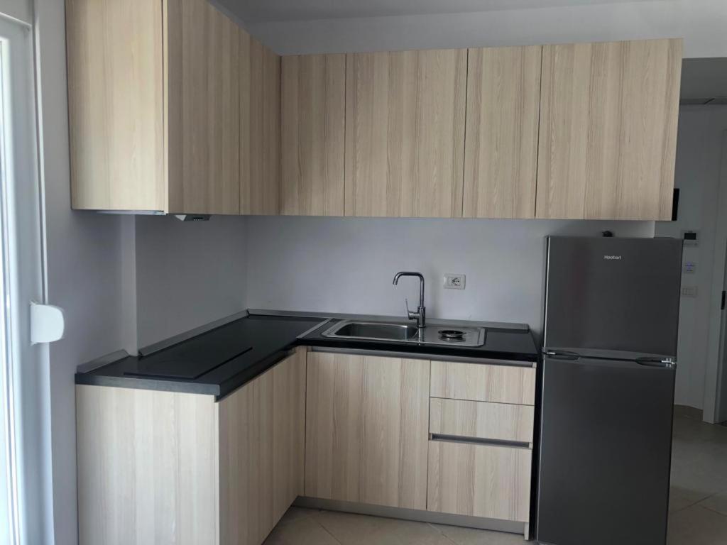 a kitchen with a black refrigerator and a sink at Hotel MARIO, Shengjin in Shëngjin